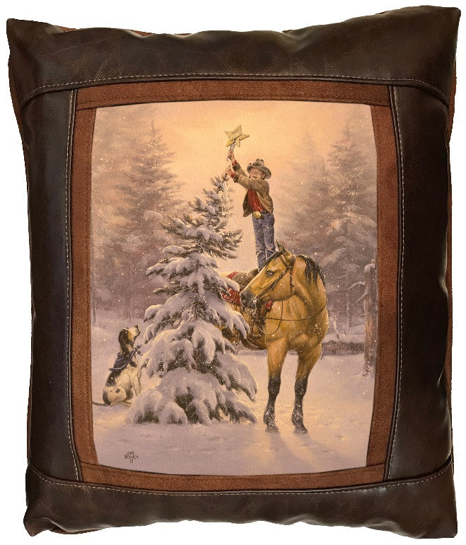 Decorative pillow with a cowboy standing on a horse, placing a star on the top of a snowy christmas tree. landscape.