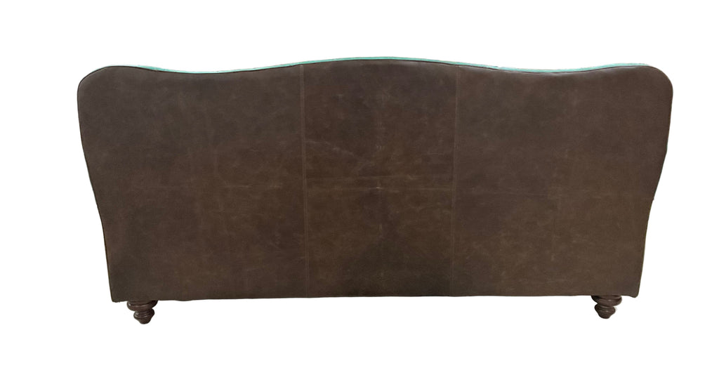 Brown sofa in a warehouse setting with various items in the background