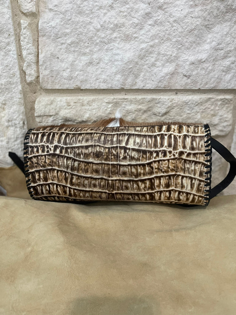 Clutch bag with crocodile texture on a stone surface