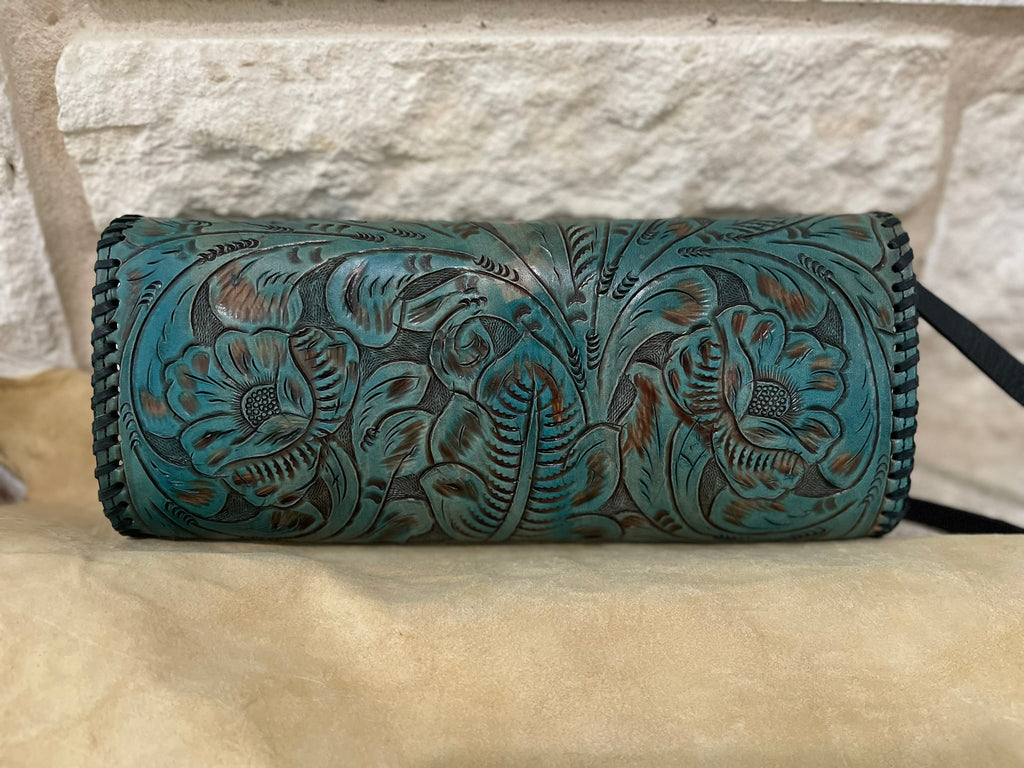 Floral embossed leather in turquoise with black lacing and black strap with stone background.