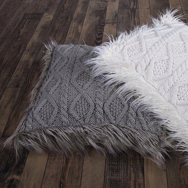 Gray textured pillow with faux fur trim on a wooden floor with partial image of white textured pillow with faux fur trim on top.