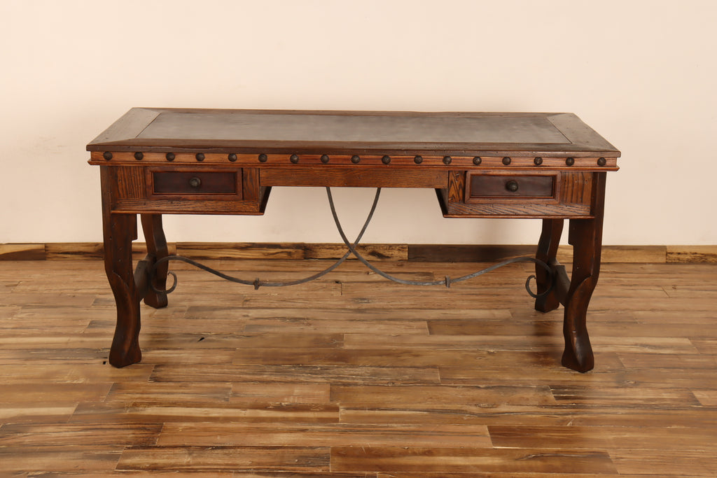 Wooden desk with leather top on a wooden floor against a beige wall