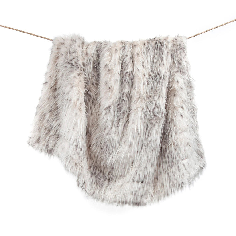 White throw faux fur blanket with variegated colors of black and gray shown hanging on a line with a white background