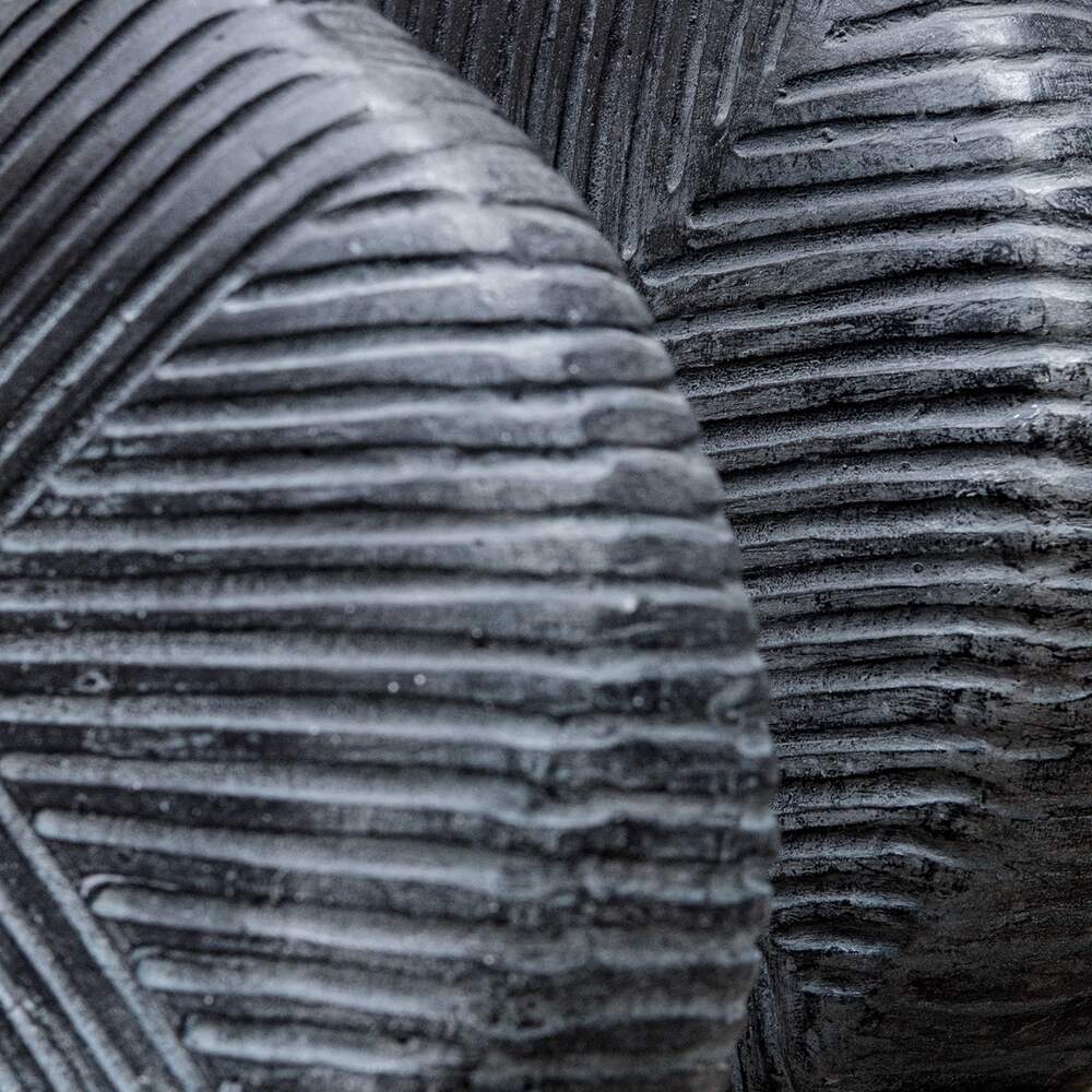 Close-up of aged black geometric vases showcasing intricate patterns and sleek off-centered openings, ideal for stylish interiors.