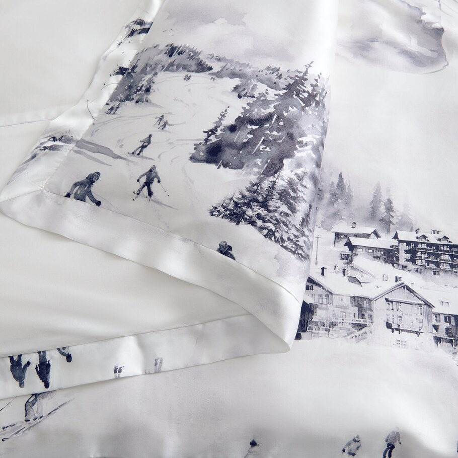 Detailed view highlighting the intricate watercolor ski scene pattern on the Alpine Lyocell Bedding Set, illustrating skiers amidst snowy terrains and alpine chalets.​