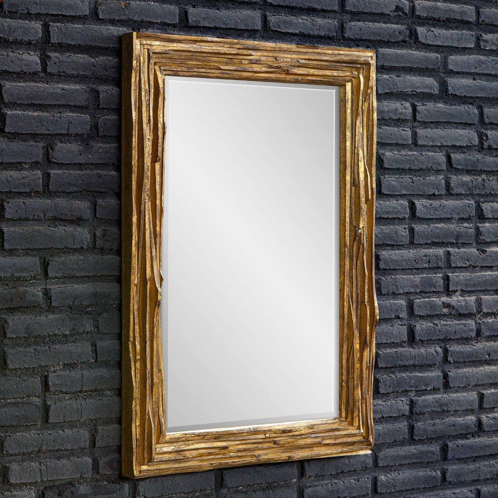raw layers of curved teackwood finished in distressed antique gold mirror frame shown at an angle on a black brick wall