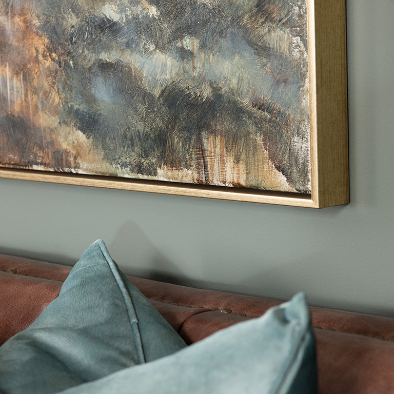 Abstract painting on a wall above a sofa with green cushions.