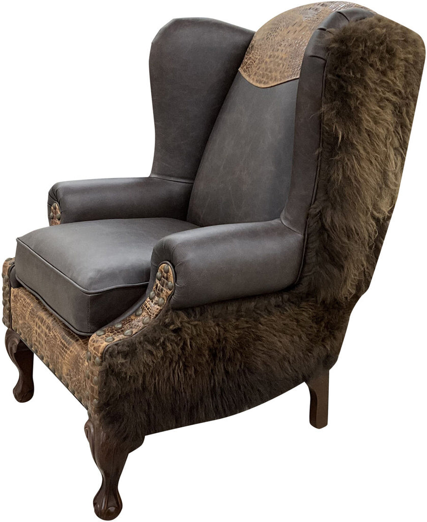 A side-angle view of the Buffalo NY Wingback Chair, highlighting its high-back winged design, buffalo hide-wrapped arms, and intricate leather detailing.