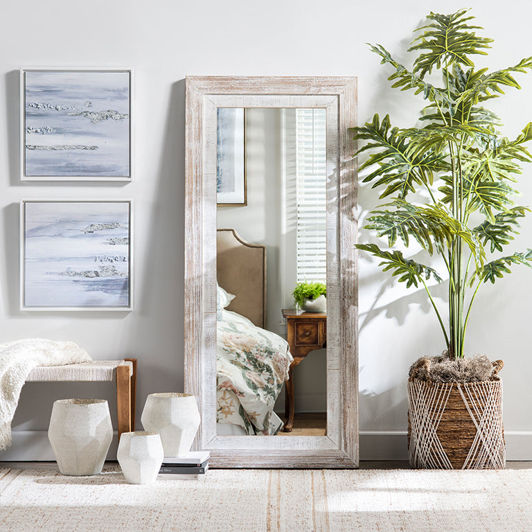 Living room with a large floor mirror, framed artwork, and a plant.