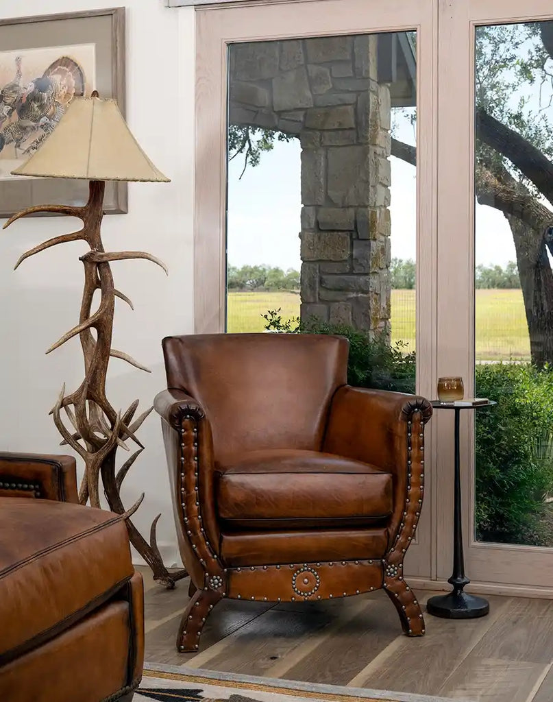 Brown leather armchair in a room with a lamp and large window.