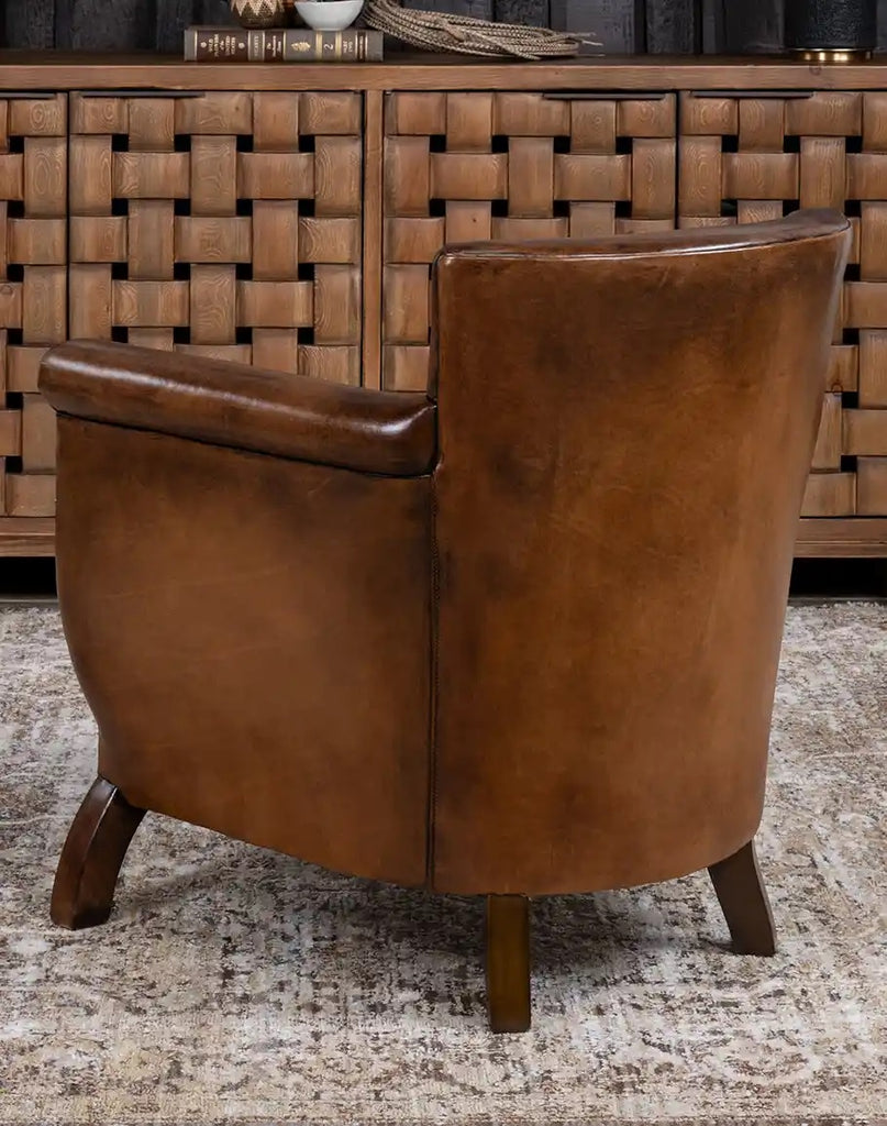 Brown leather armchair in front of a wooden cabinet with woven design.