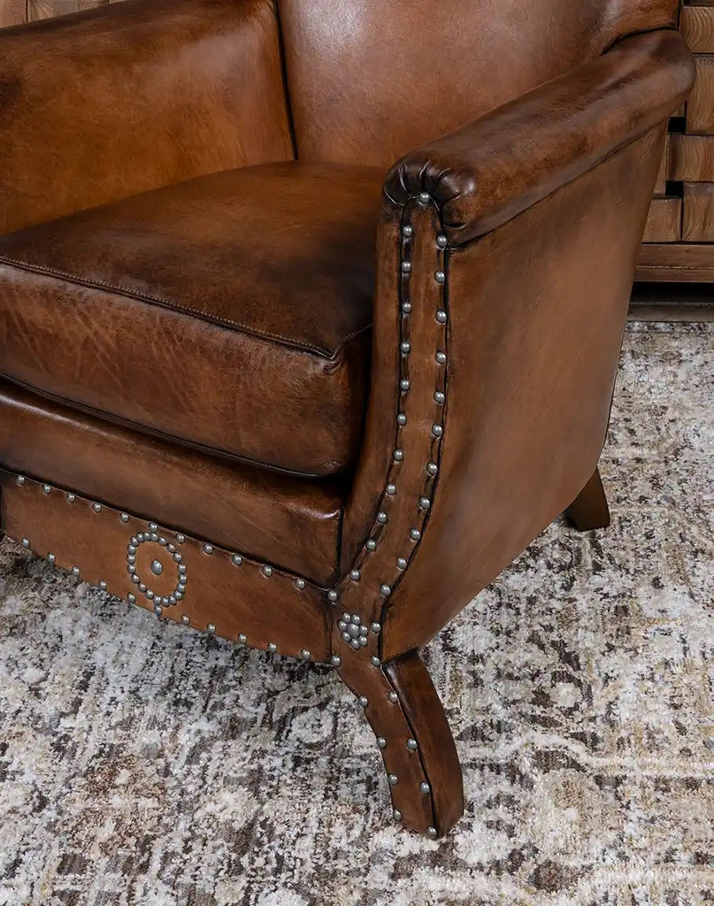Brown leather sofa with nailhead trim on a textured rug