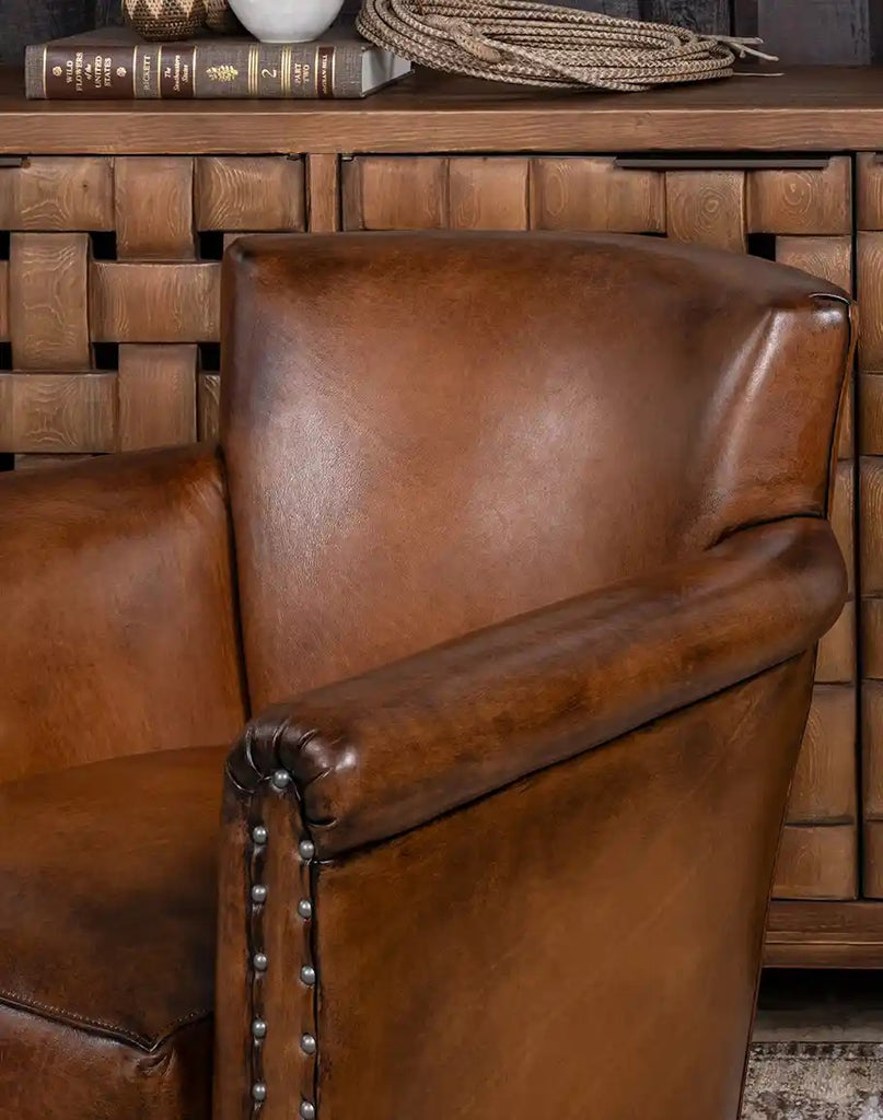 Brown leather armchair in front of a wooden cabinet with books and a rope.