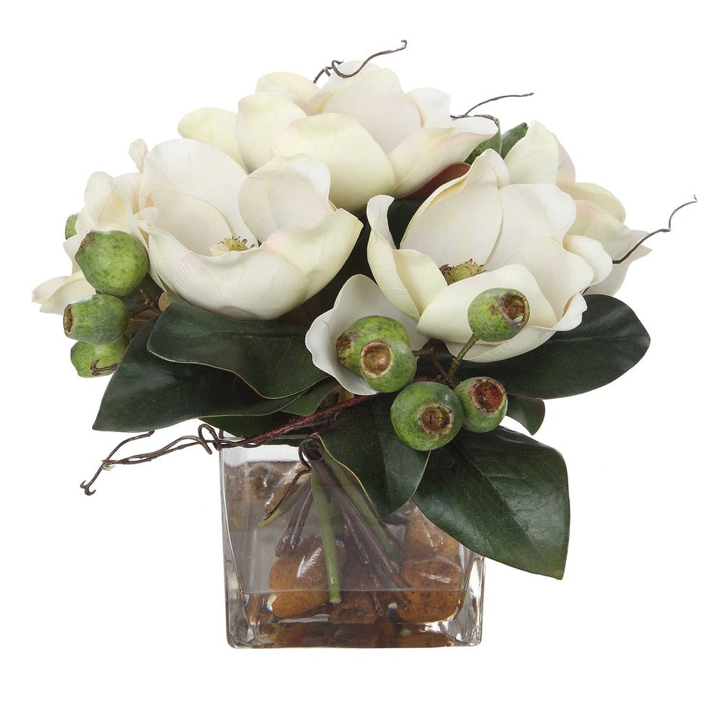 A beautifully arranged white magnolia bouquet with natural river stones and faux water, set in a sleek square glass vase.