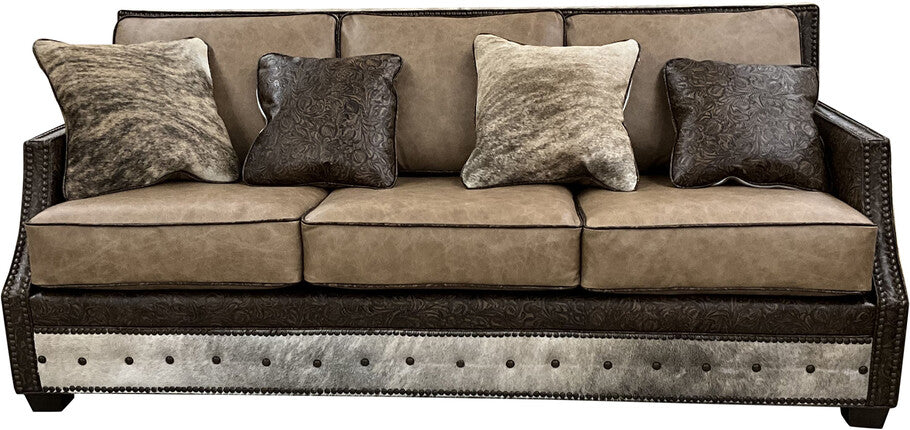 The Frio River Sofa, upholstered in Palio Camel leather with Floral Bone Black accents and exotic cowhide detailing, showcases its elegant Western-inspired design in a warm, inviting setting.