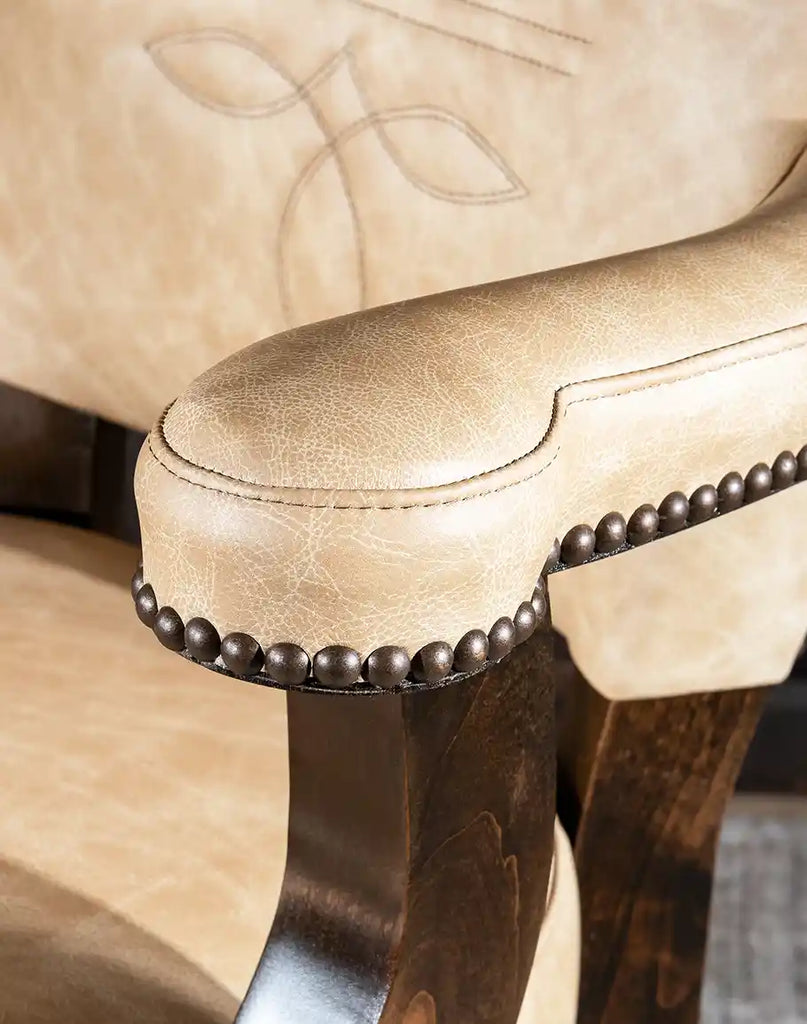 Close-up of the armrest detailing on the Chisum TX Paraluman Barstool with brass nailhead trim.