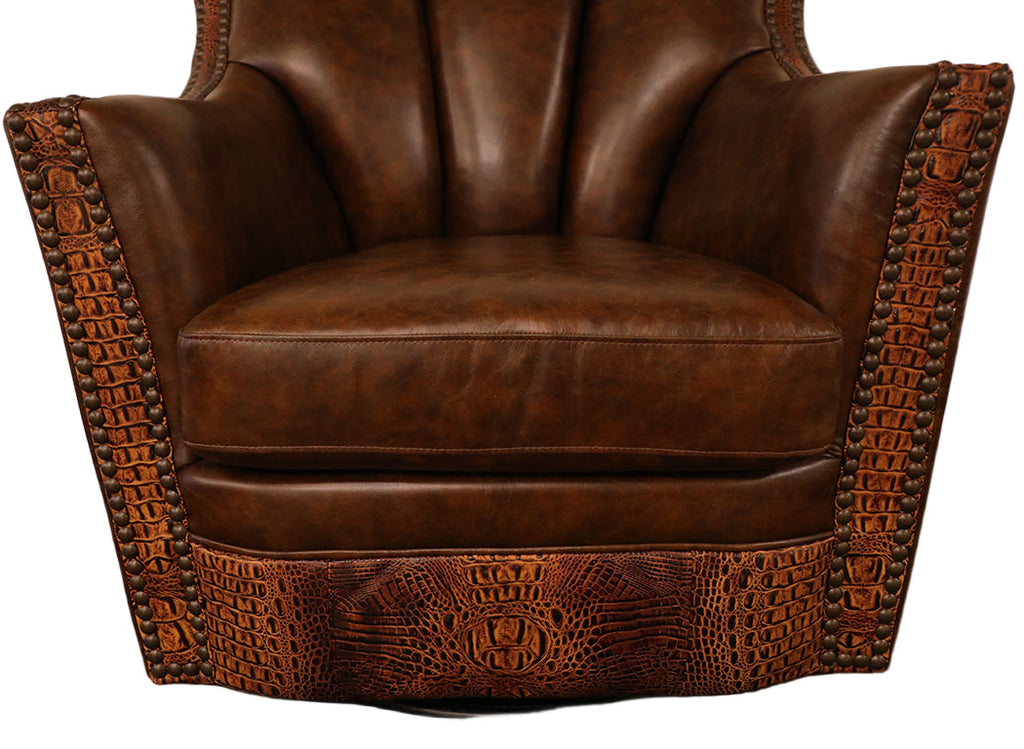 Close up on bottom of swivel glider chair featuring embossed butternut leather on the front arm posts and seat rail. Nailhead trim and brown leather seat and inback.