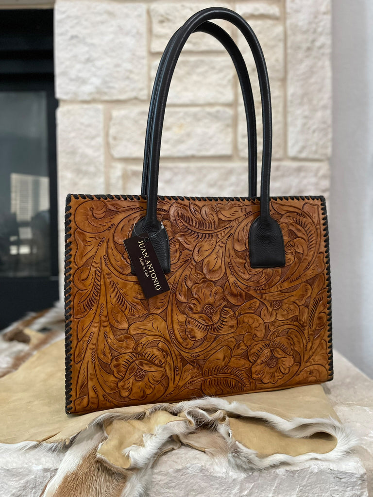 Saddle tan brown leather handbag with intricate floral embossed patterns and smooth brown straps.