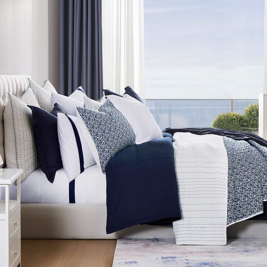 Legato Reversible Quilt Set styled in a coastal-themed bedroom, complemented by light wood furnishings and ocean-inspired decor elements.​