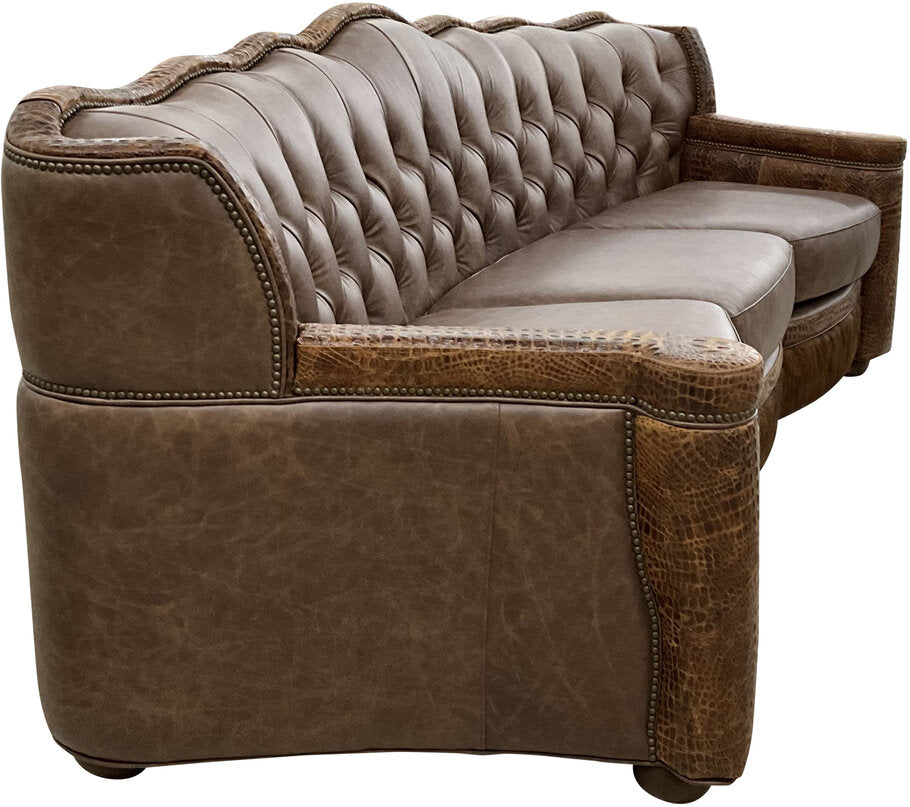 A detailed shot of the Marshland Curved Sofa’s Palio Cafe leather upholstery, Gator Hornback Rustic Cognac accents, and dark exotic cowhide bottom rail.