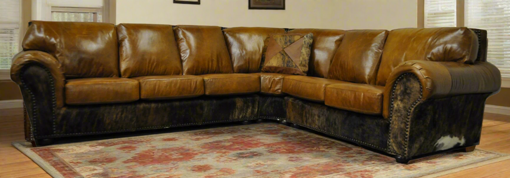 Brown leather sectional sofa with three seats, a pie section that connects to a two seat loveseat with cowhide accents on front arm panel, sides and back in a living room setting with a patterned rug