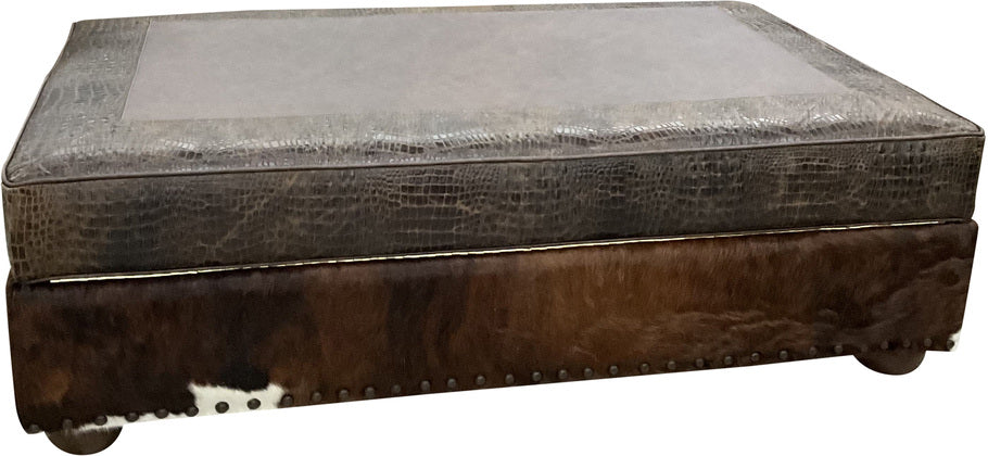 Front view of the Palio Dark Brown Storage Ottoman featuring Gator Hornback Rustic Walnut leather, a luxurious Palio Dark Brown leather top, and dark exotic with white brindle cowhide on the base with nailhead trim accents.