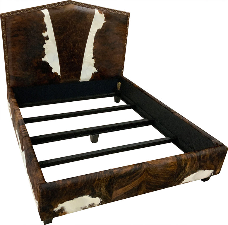 Angled top view of bed with cowhide leather headboard, footboard, and side rails on a white background