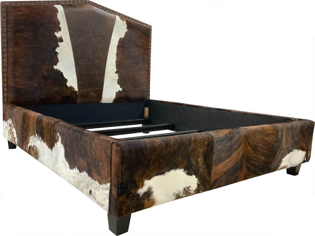 Side view of bed with cowhide leather headboard, footboard, and side rails on a white background