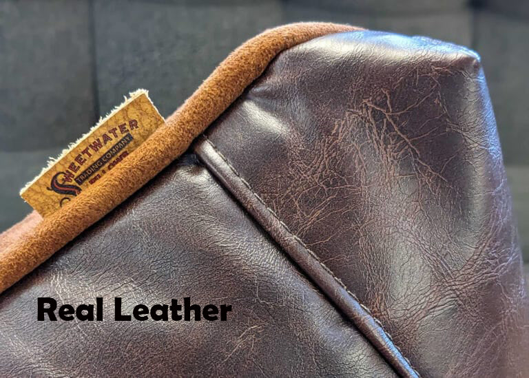 Corner of brown faux leather pillow with a brand tag on a blurred background