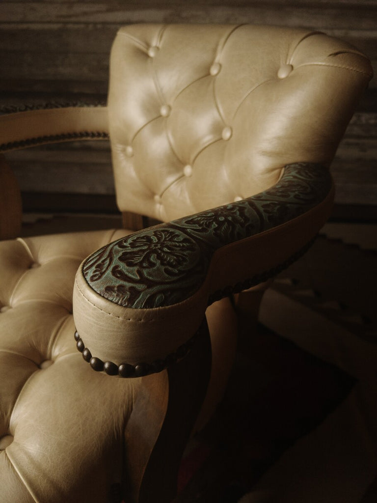 Side angle of the Rio Grande Tufted Barstool highlighting the elegant curves, light brown frame stain, and Floral River Reed accent leather on the arms.