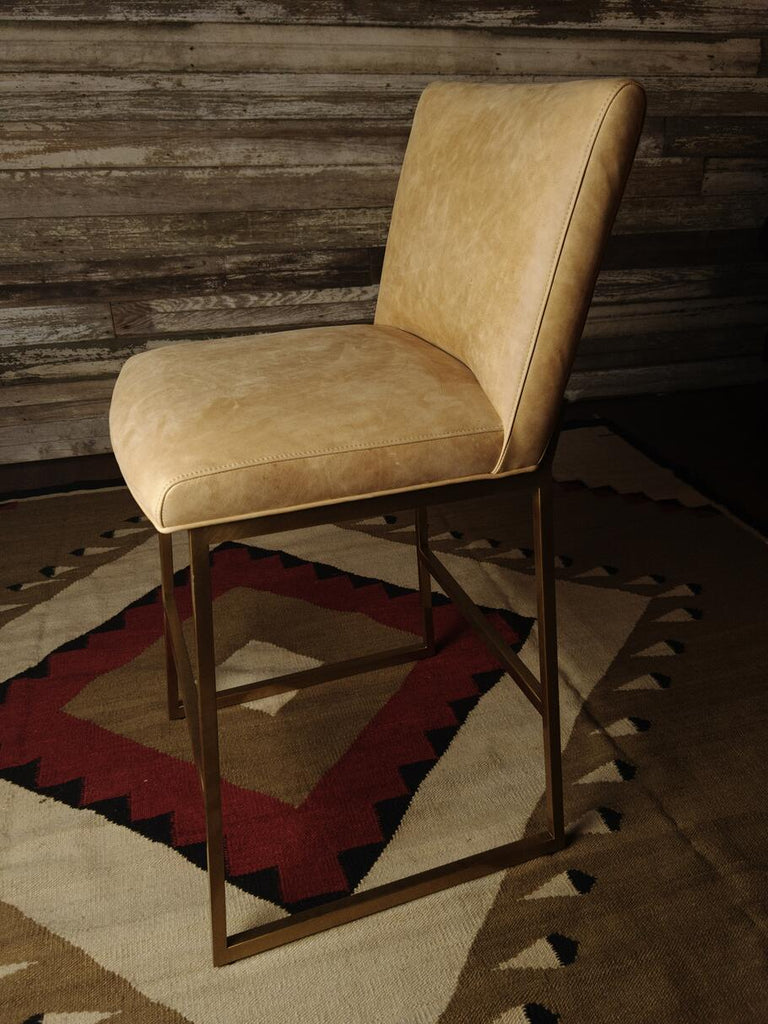 Side profile of the Roaring Fork Valley Barstool, highlighting the seamless integration of modern and Western design elements in its brass frame and leather seat.