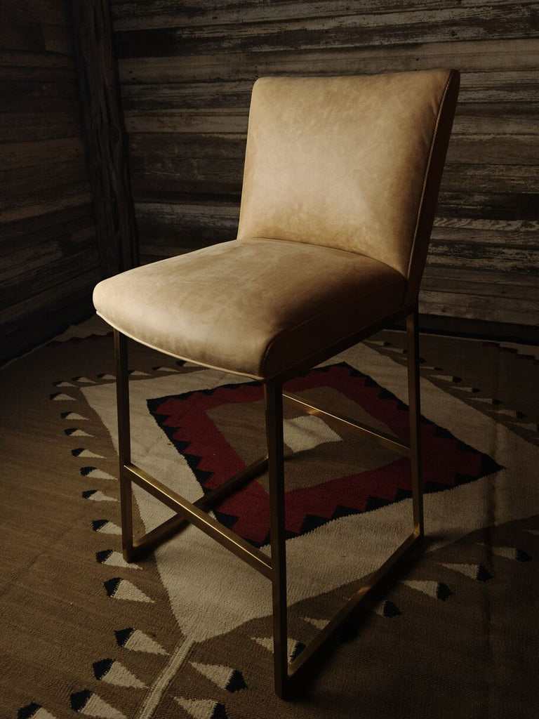 Roaring Fork Valley Barstool showcasing its sleek design, rich Burnham Sunset leather upholstery, and minimalist brass metal frame.