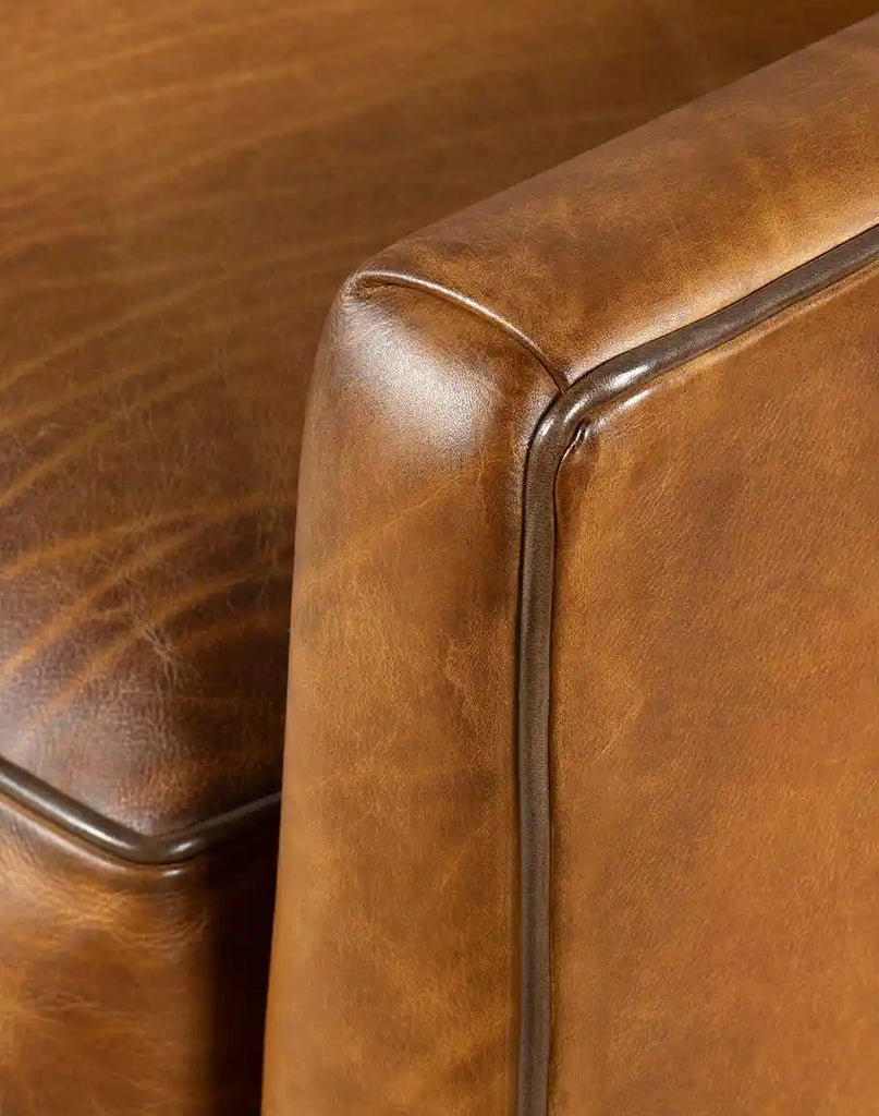 Close-up image capturing the rich texture and hand-burnished details of the Rudy Saddle Leather Sofa's full-grain leather.