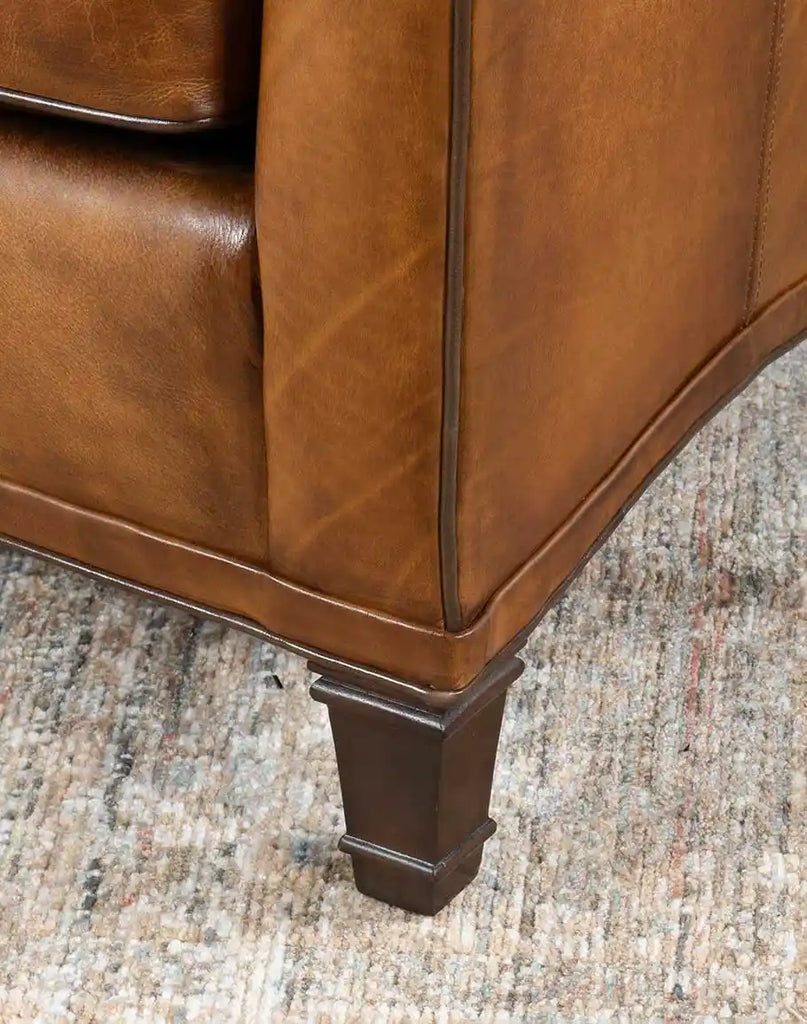 Close-up of the Rudy Saddle Leather Sofa's sturdy wooden legs supporting its handcrafted frame.