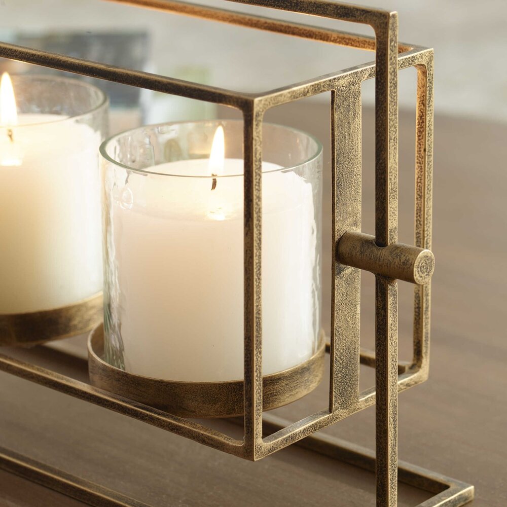 Antique gold candle lantern with a three-candle setup, clear textured glass hurricanes, and an iron base, perfect for adding warmth to any room.