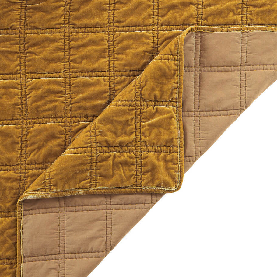 Close-up of the quilt's corner, displaying the precise stitching and plush velvet texture in a soothing saffron shade.