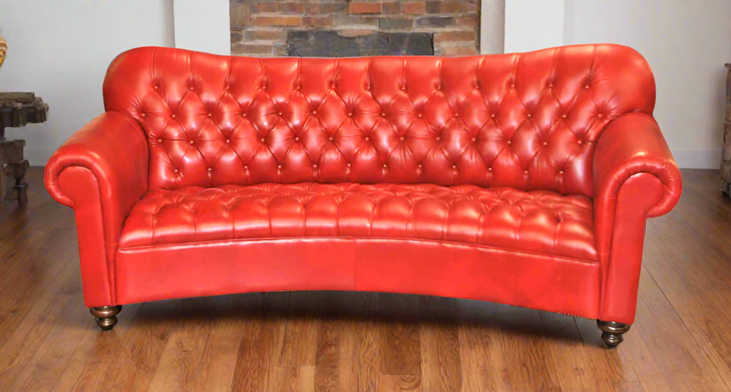 Red leather sofa on a wooden floor with a brick fireplace in background on a wooden floor.