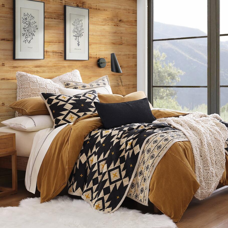 Queen-sized Sonoran Desert Reversible Quilt Set featuring bold Southwestern geometric patterns in black, Tuscan yellow, and light tan hues.​