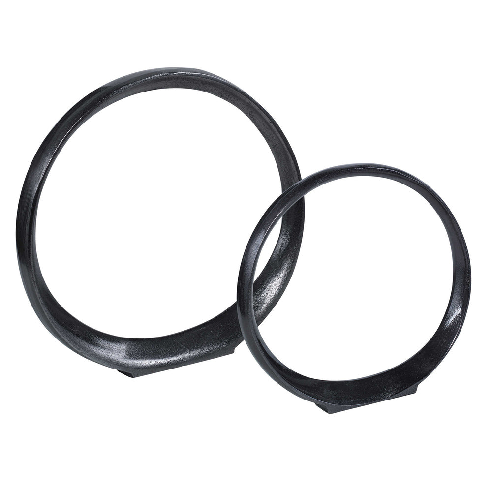 Set of small and large black nickel Loop Ring Sculptures displayed on a table.