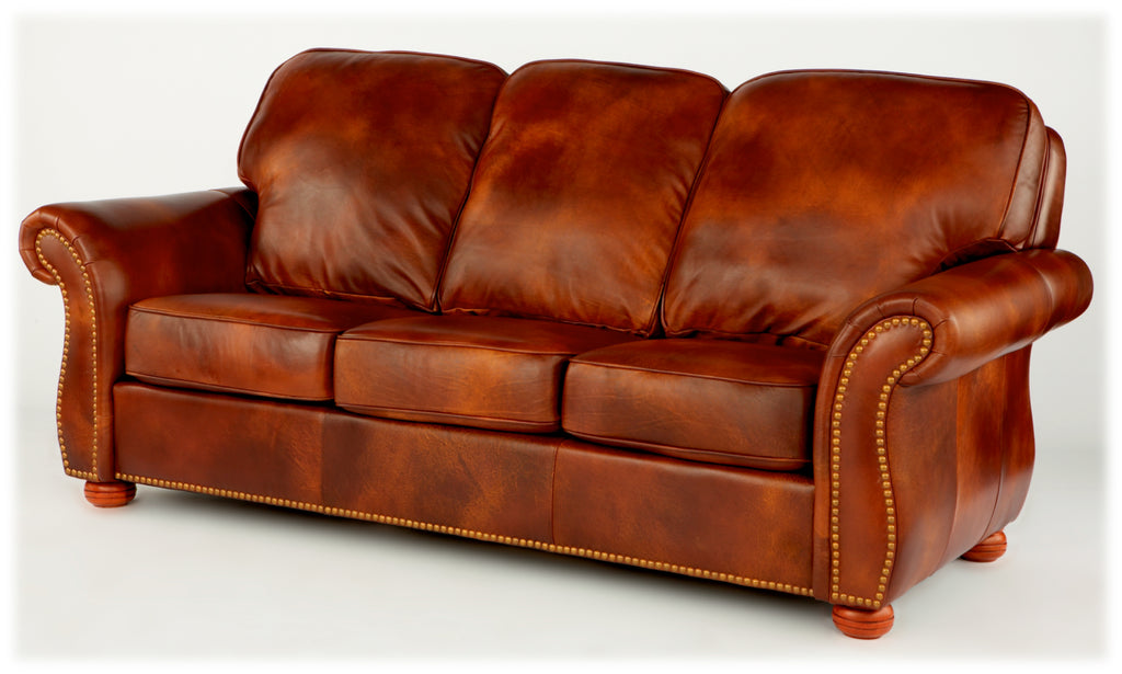 Brown leather three seat sofa with antique nailhead trim with rolled arms on a white background