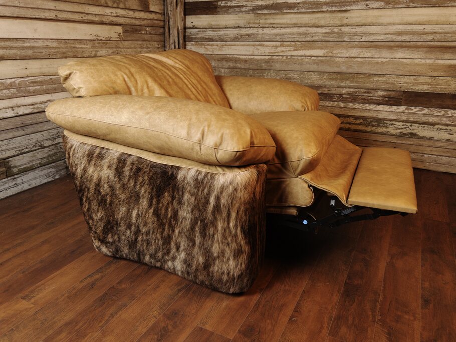 The Texas Longhorn Recliner in a fully reclined position, showcasing its plush Longhorn Oatmeal leather upholstery, medium exotic brindle cowhide sides, and extended footrest. Set against a rustic wooden backdrop, this oversized recliner combines luxury, comfort, and Western elegance.