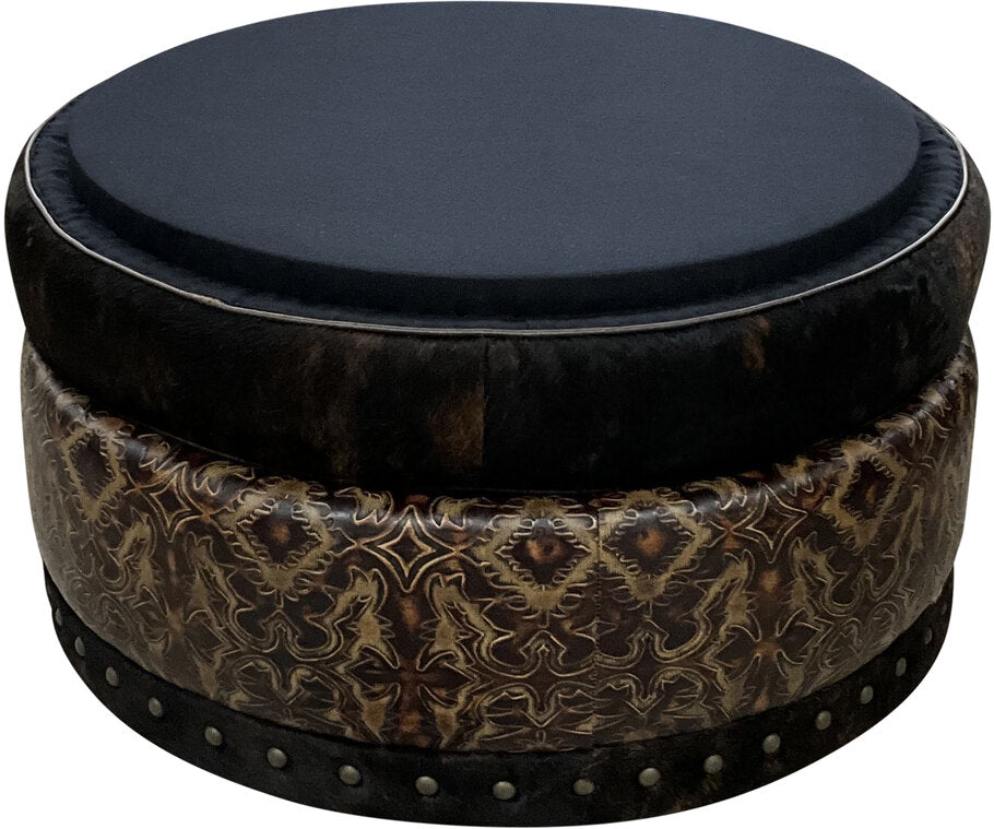 A multi-functional leather and cowhide ottoman in a living space, ideal as extra seating, a footrest, or a stylish accent piece for rustic and contemporary interiors.