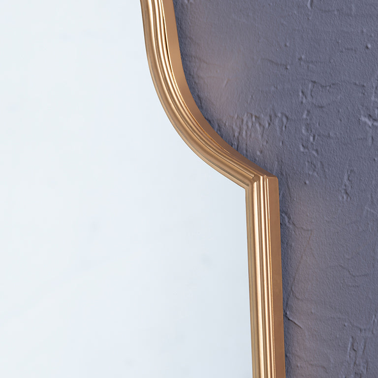 close up of gold mirror against a textured gray wall