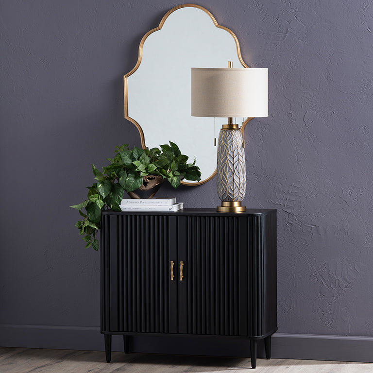 Black cabinet with a lamp and plant against a dark gray wall