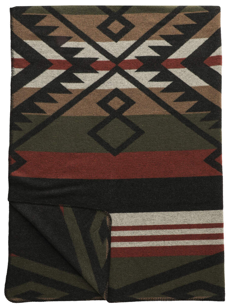 Wooded River Paloma Earth Throw featuring a rich blend of Spice, Sage, and Camel tones with hints of tan, black, and red, crafted from a washable wool blend; draped on a bed for a cozy, rustic aesthetic.