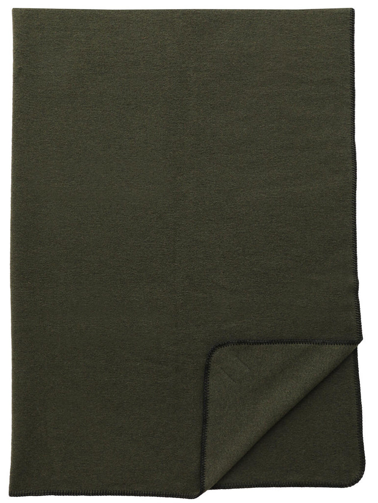 Solid Sage 60x72 Throw by Wooded River draped on a bed, showcasing its soft sage green hue, decorative blanket stitching, and premium Italian wool-blend fabric—crafted with up to 90% recycled fibers for sustainable elegance.