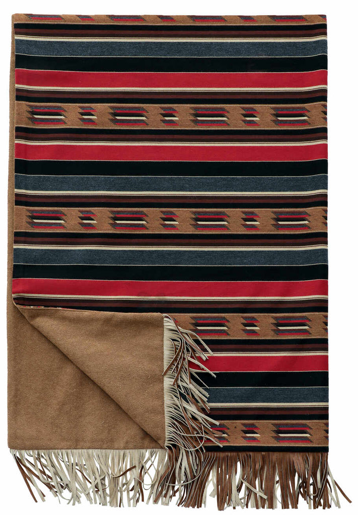 Wooded River Sun Valley Mojave Throw featuring a bold Southwestern geometric pattern in tan, cream, browns, black, red, and blue-grey on Sunbrella fabric, backed with soft Nougat fabric and finished with genuine cowhide fringe; a cozy and stylish accent for rustic or modern décor.